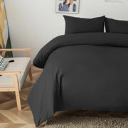 Housse de couette noire unie sur l'angle d'un lit avec taies assorties