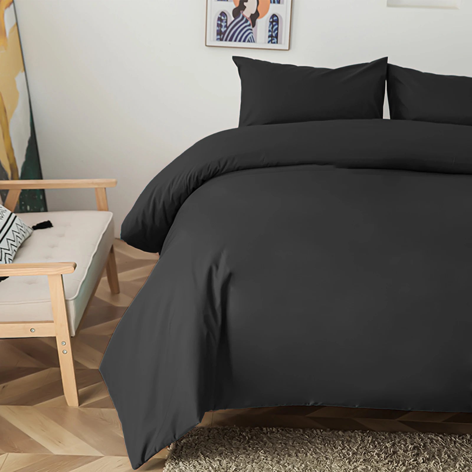 Housse de couette noire unie sur l'angle d'un lit avec taies assorties